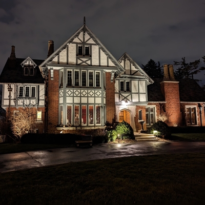 Beautiful Tudor-style home with curb appeal lighting to make the house shine after dark. Photo